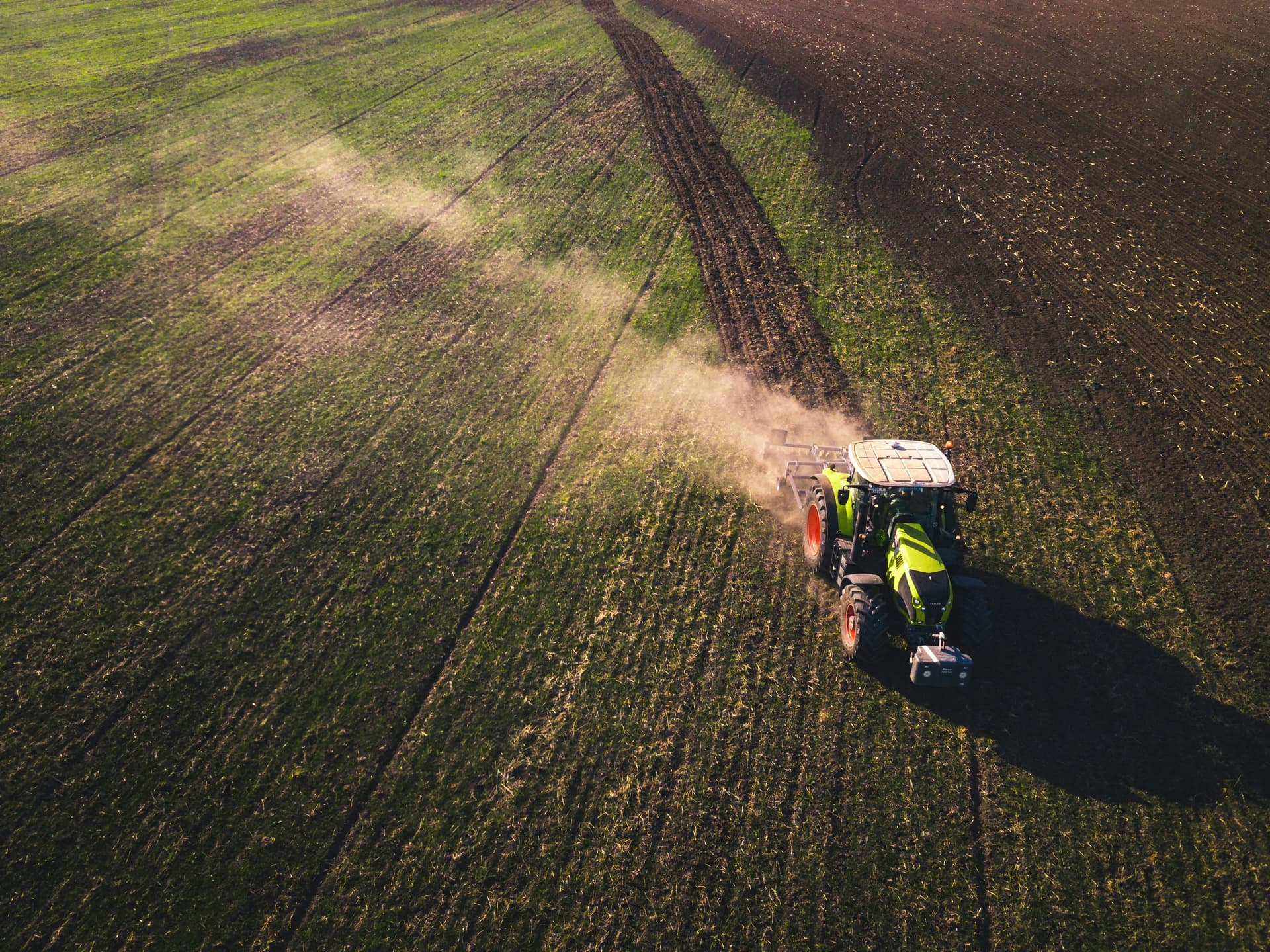 A tractor spreads fertiliser across a broadacre paddock.